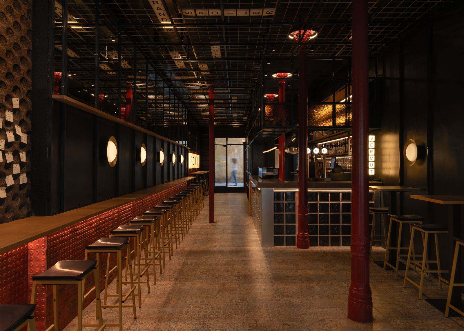 The bar at FOMO Bar: round lit wall lamps, red tiled bar front, red columns and the VERMUT light box at the back.