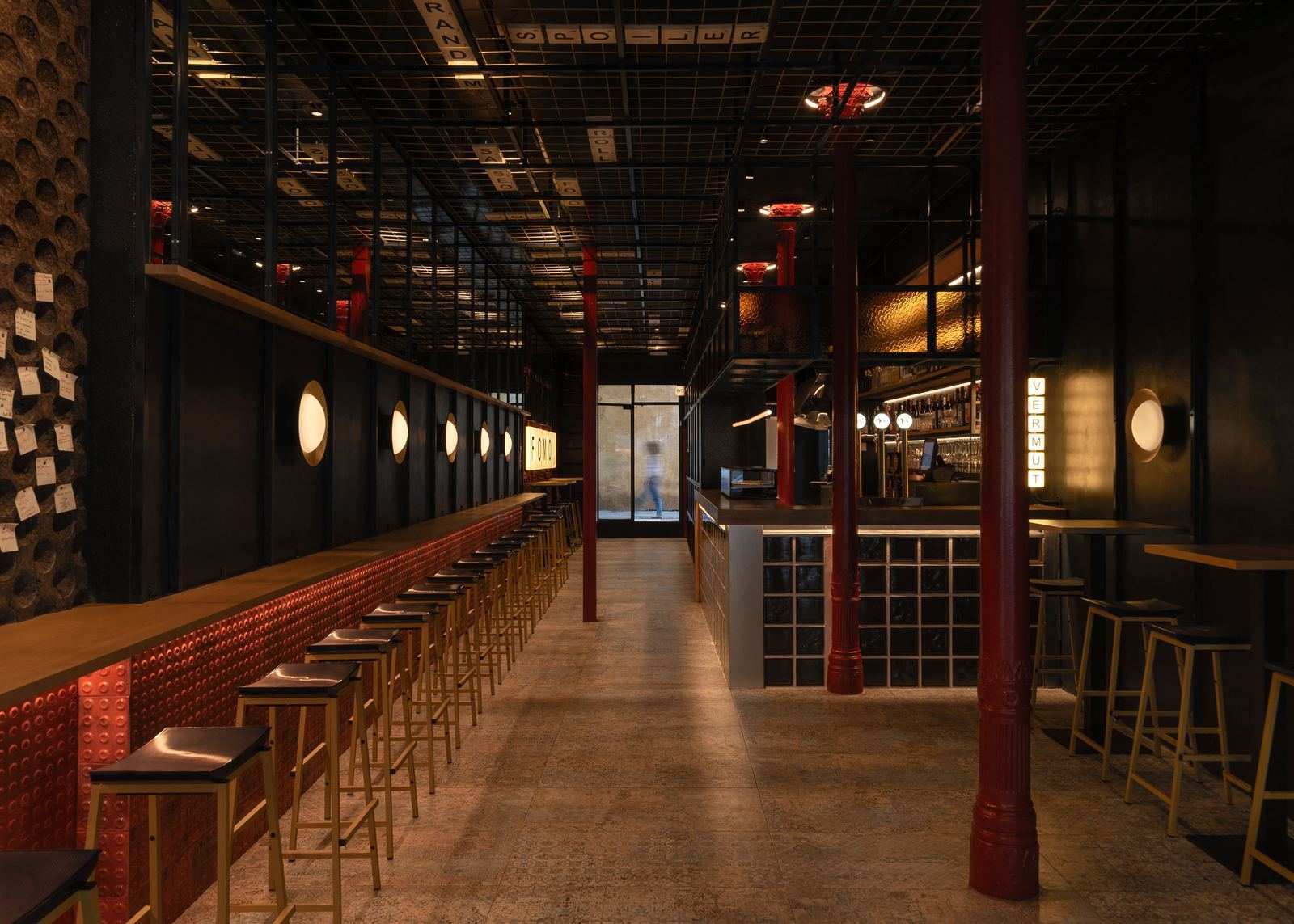 The bar at FOMO Bar: round lit wall lamps, red tiled bar front, red columns and the VERMUT light box at the back.
